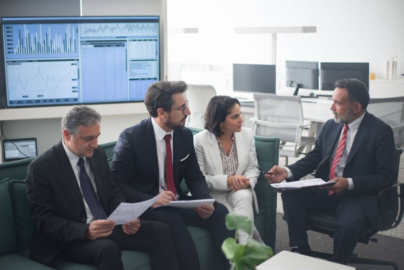 Gestores analisando relatórios diante de painel de dados